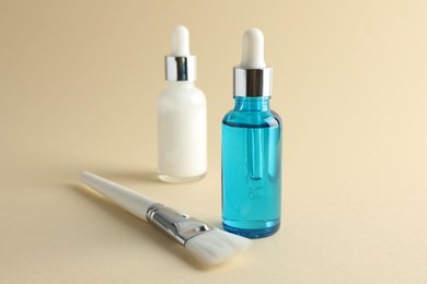 Bottles of chemical peel and brush on beige background, closeup. Peeling procedure