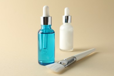 Photo of Bottles of chemical peel and brush on beige background, closeup. Peeling procedure