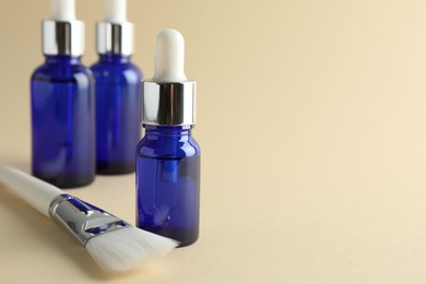 Photo of Peeling procedure. Bottles of chemical peel and brush on beige background, closeup. Space for text