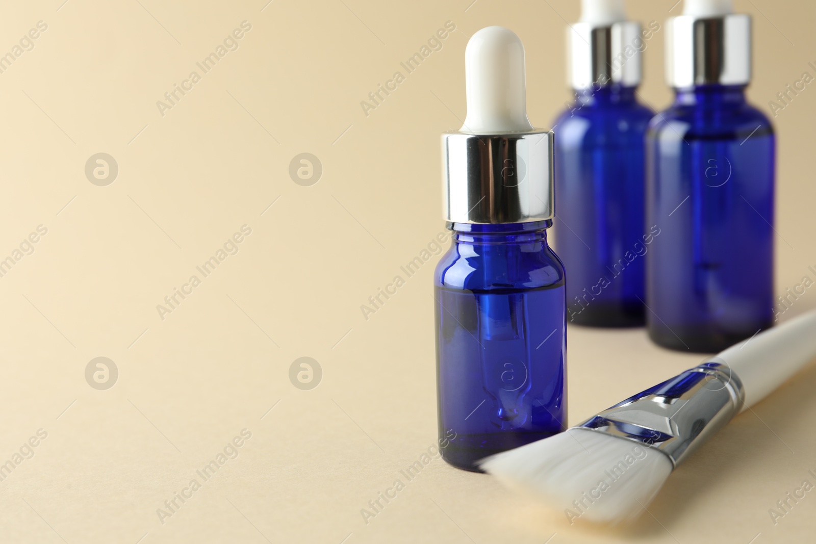 Photo of Peeling procedure. Bottles of chemical peel and brush on beige background, closeup. Space for text