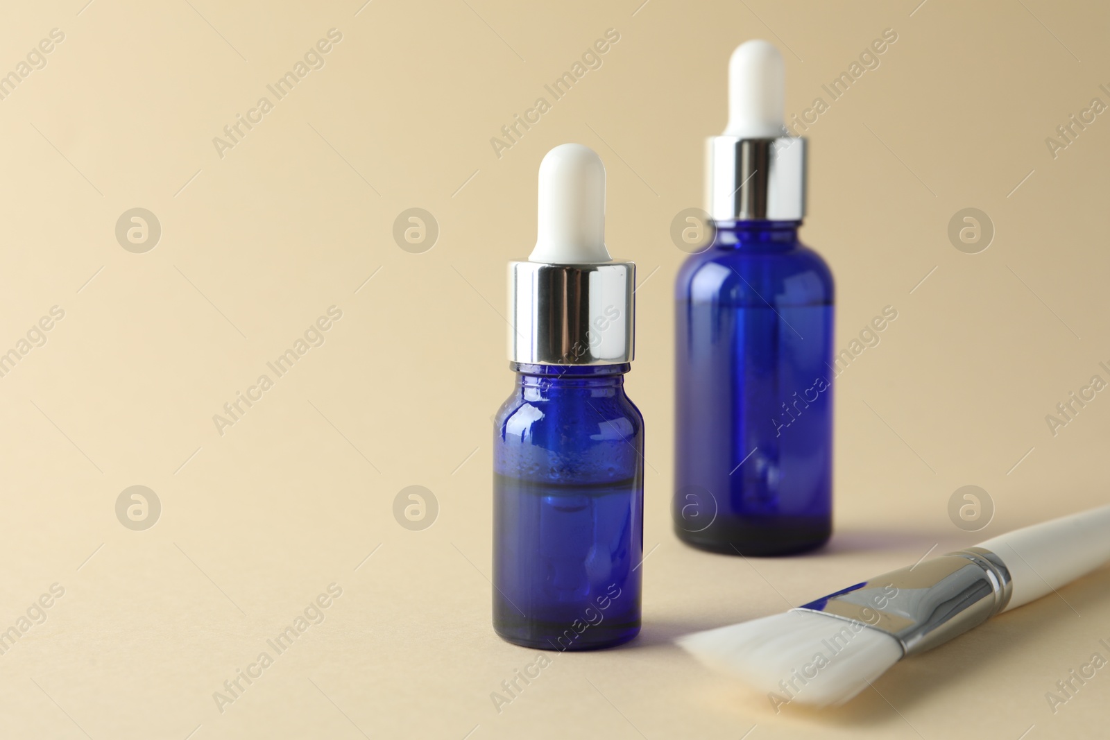 Photo of Bottles of chemical peel and brush on beige background, space for text. Peeling procedure