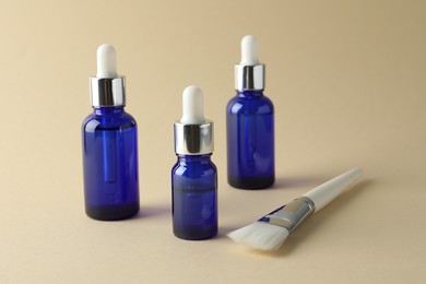 Photo of Bottles of chemical peel and brush on beige background. Peeling procedure