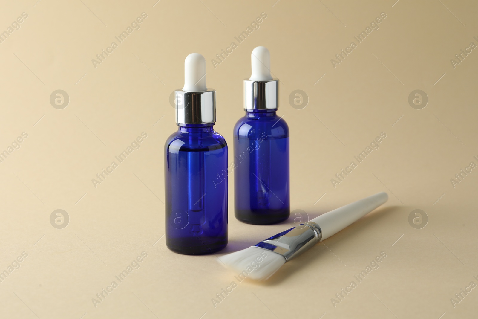 Photo of Bottles of chemical peel and brush on beige background. Peeling procedure