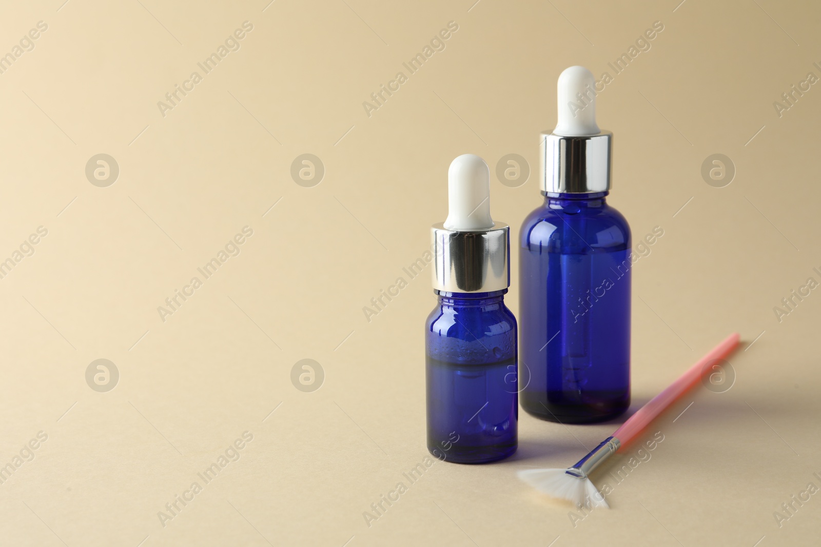 Photo of Bottles of chemical peel and brush on beige background, space for text. Peeling procedure