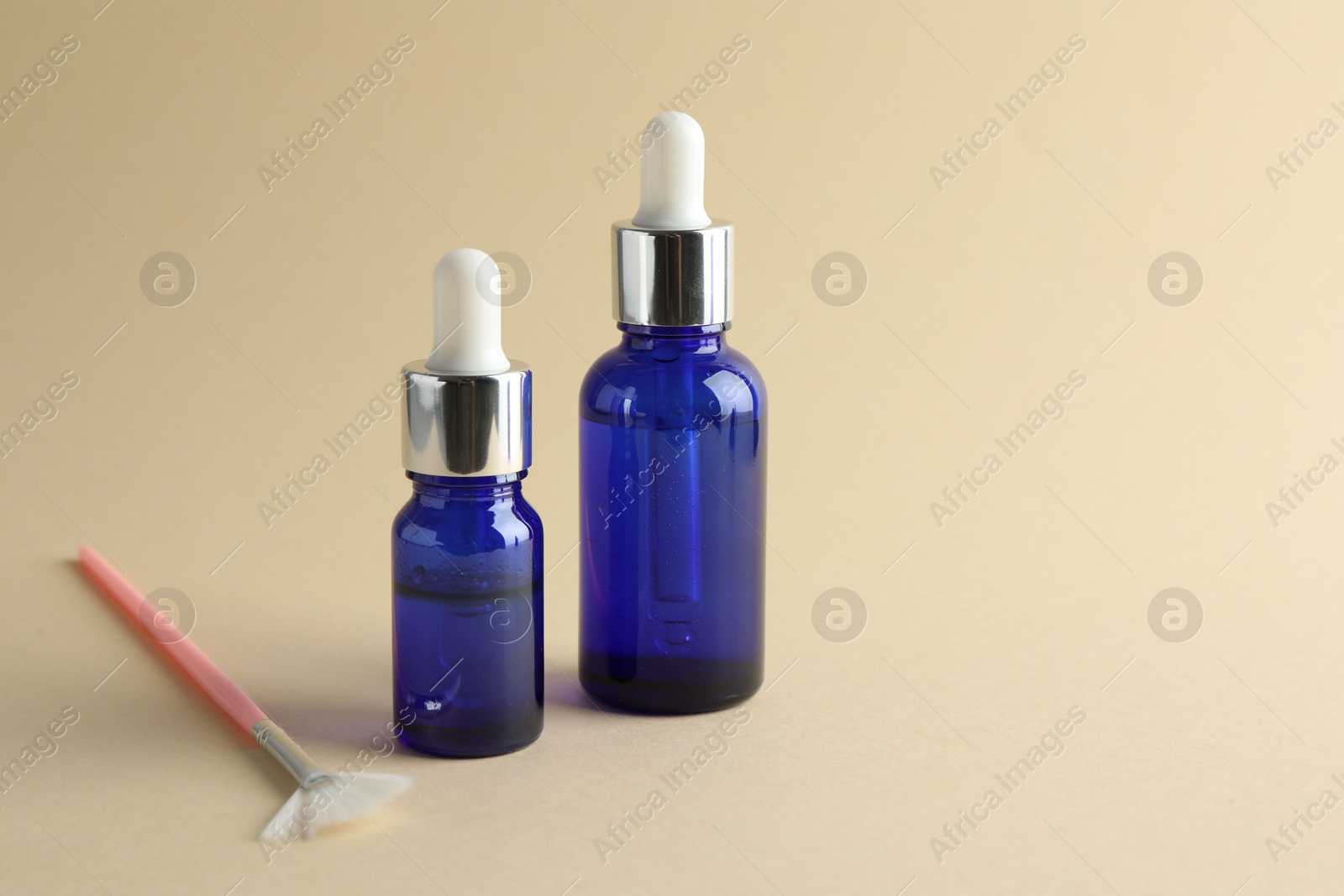 Photo of Bottles of chemical peel and brush on beige background, space for text. Peeling procedure