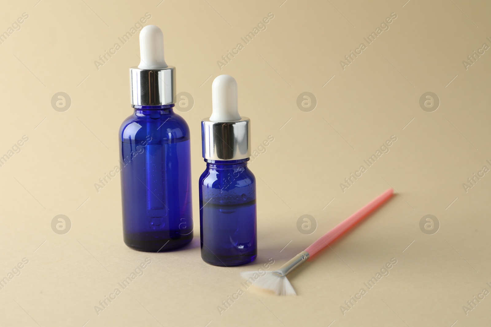 Photo of Bottles of chemical peel and brush on beige background, space for text. Peeling procedure