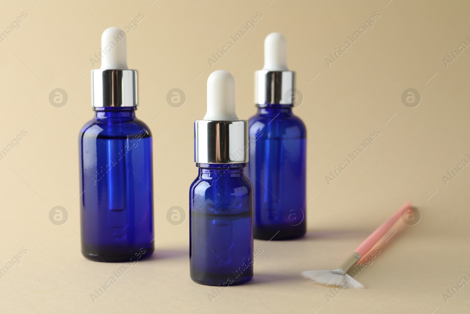 Photo of Bottles of chemical peel and brush on beige background. Peeling procedure