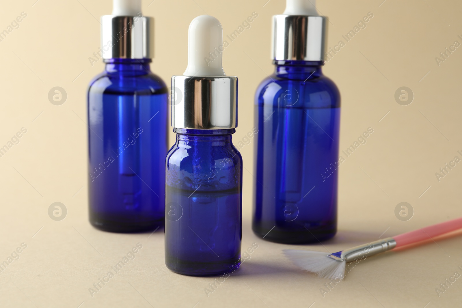 Photo of Bottles of chemical peel and brush on beige background, closeup. Peeling procedure