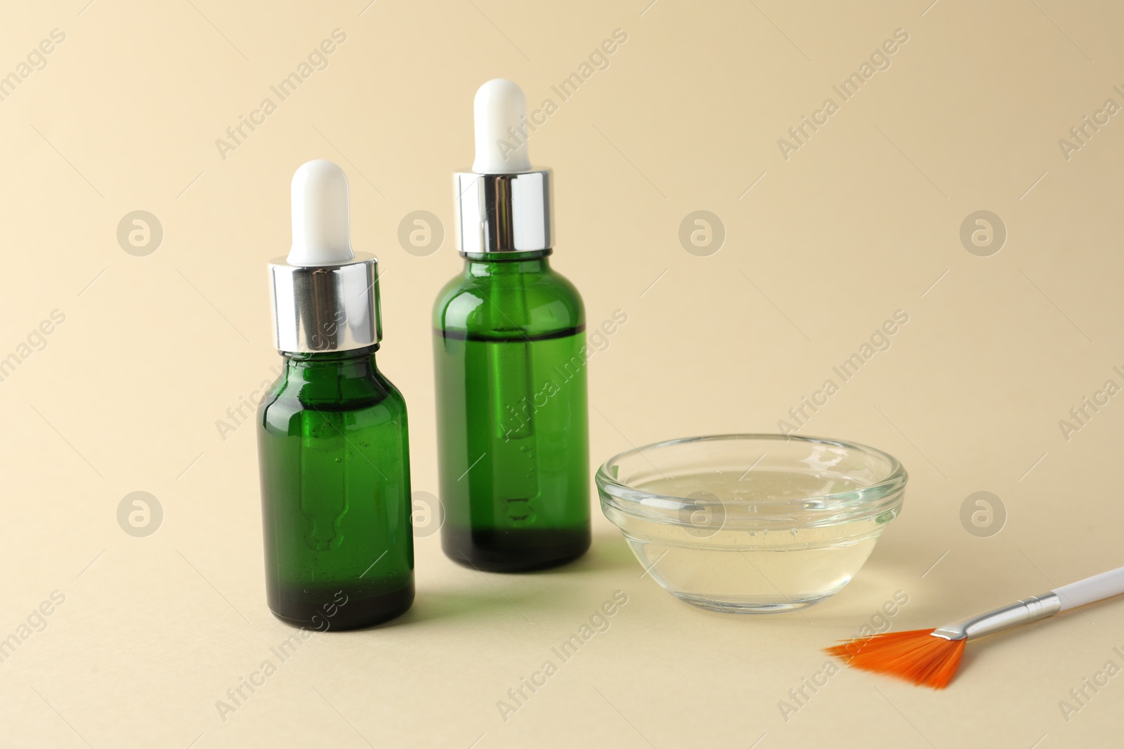 Photo of Bottles of chemical peel, bowl with liquid and brush on beige background. Peeling procedure