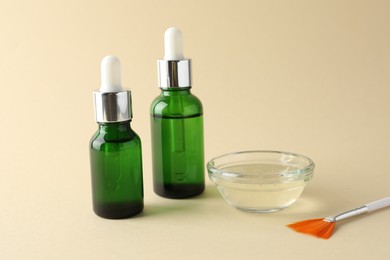 Bottles of chemical peel, bowl with liquid and brush on beige background. Peeling procedure