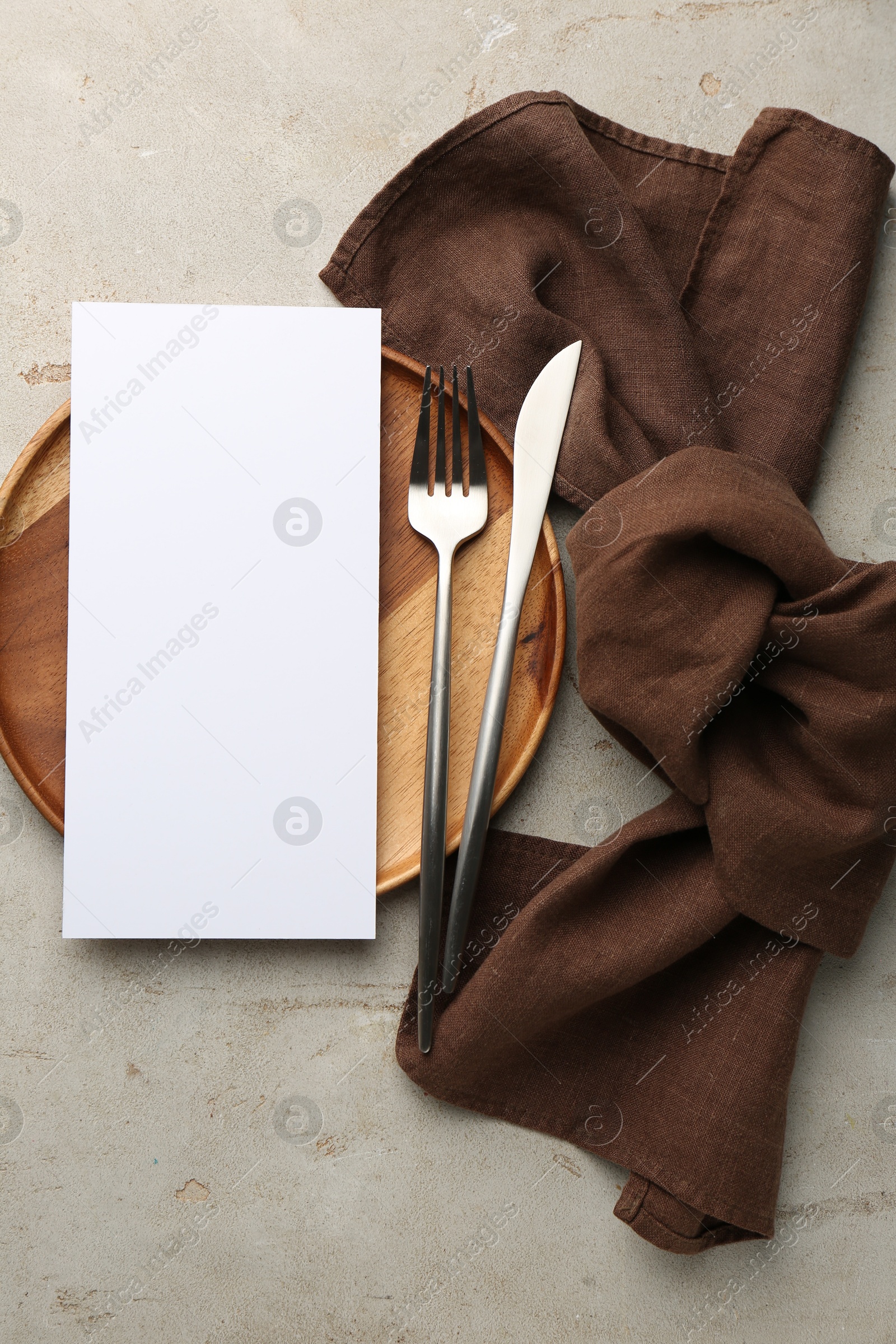 Photo of Empty menu, plate, cutlery and napkin on light grey table, top view. Mockup for design