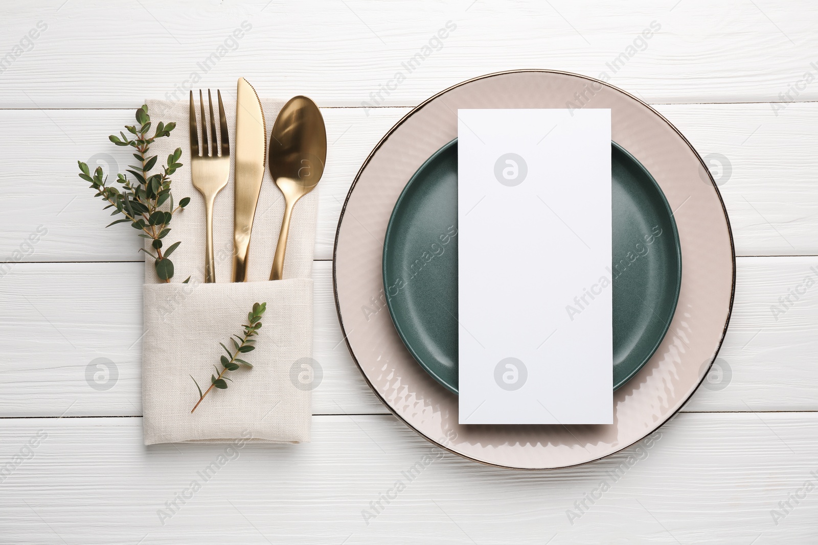 Photo of Empty menu, plates, cutlery, napkin and floral decor on white wooden table, top view. Mockup for design