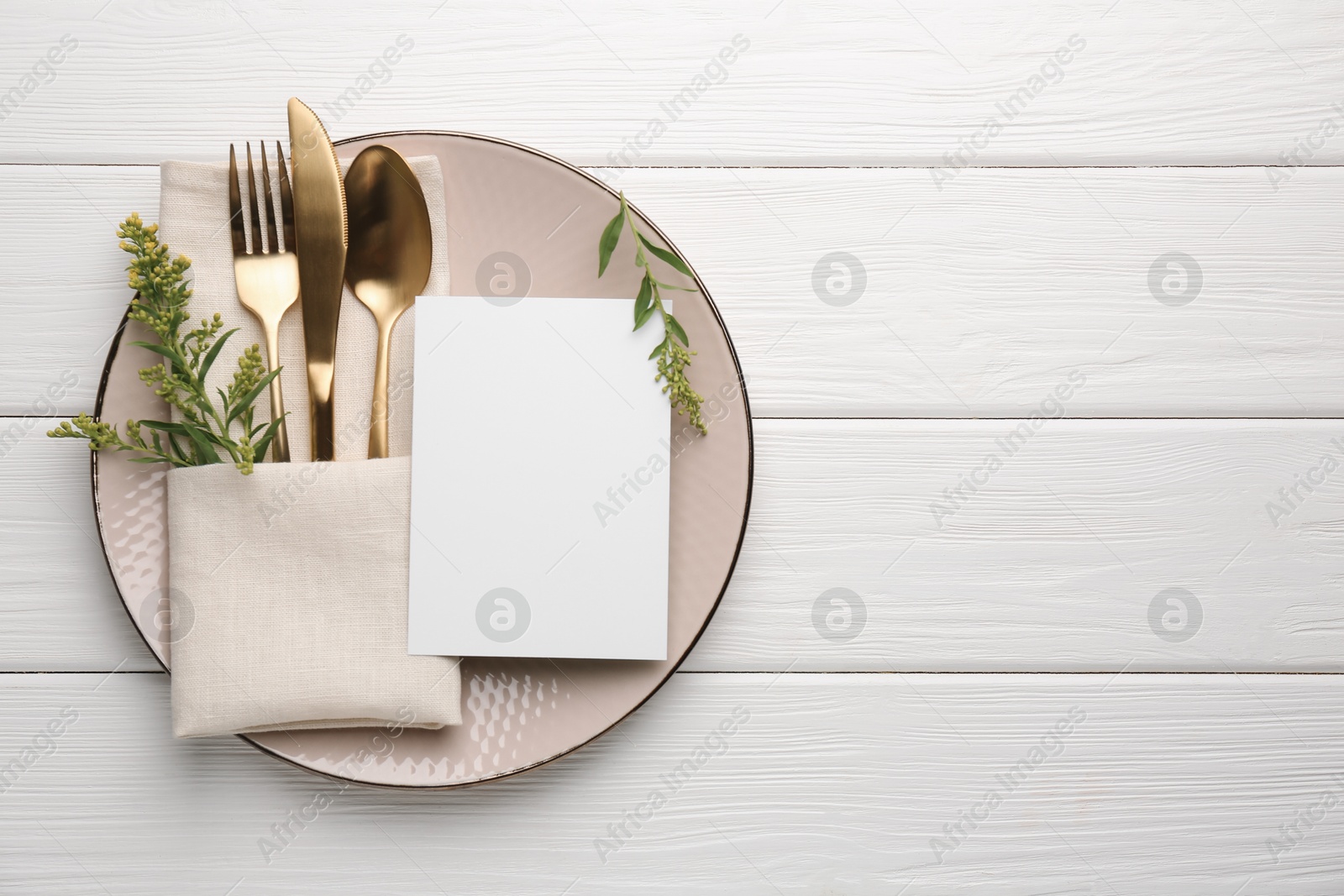 Photo of Empty menu, plate, cutlery, napkin and floral decor on white wooden table, top view. Mockup for design