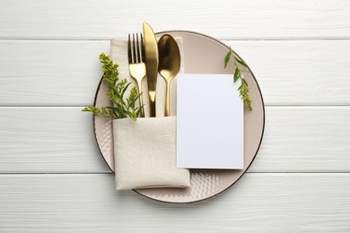 Photo of Empty menu, plate, cutlery, napkin and floral decor on white wooden table, top view. Mockup for design