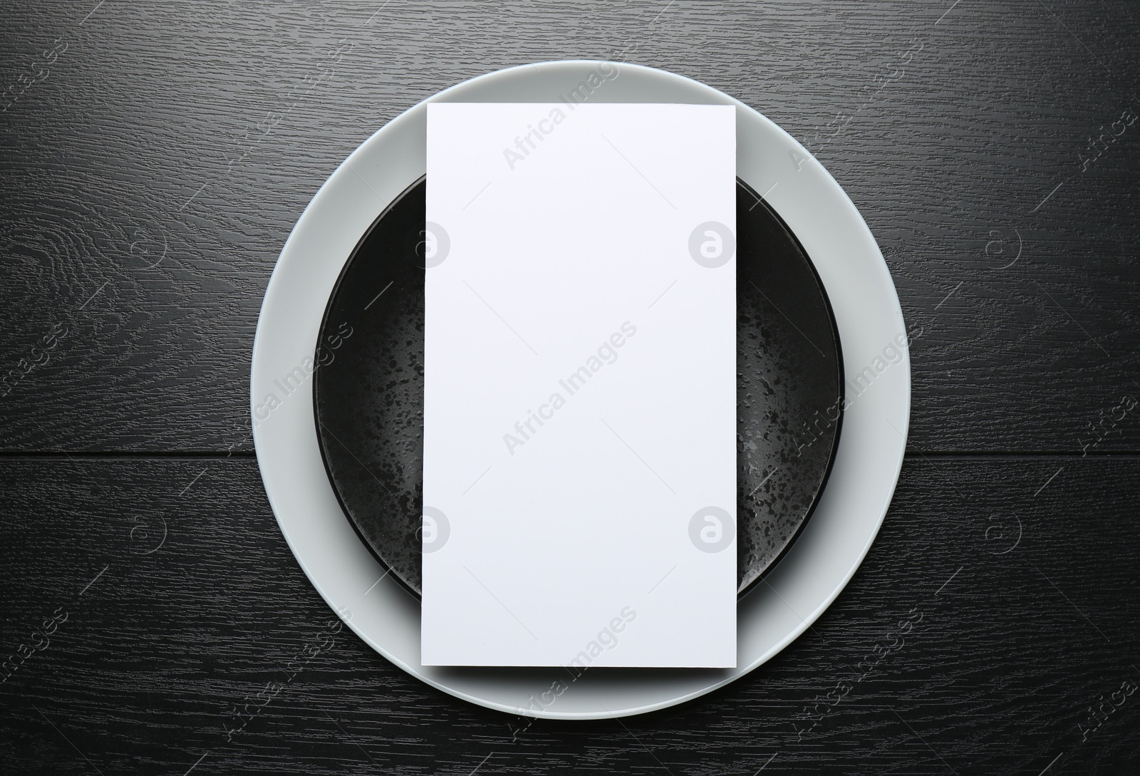 Photo of Empty menu and plates on black wooden table, top view. Mockup for design