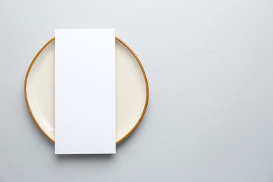 Empty menu and plate on light grey background, top view. Mockup for design