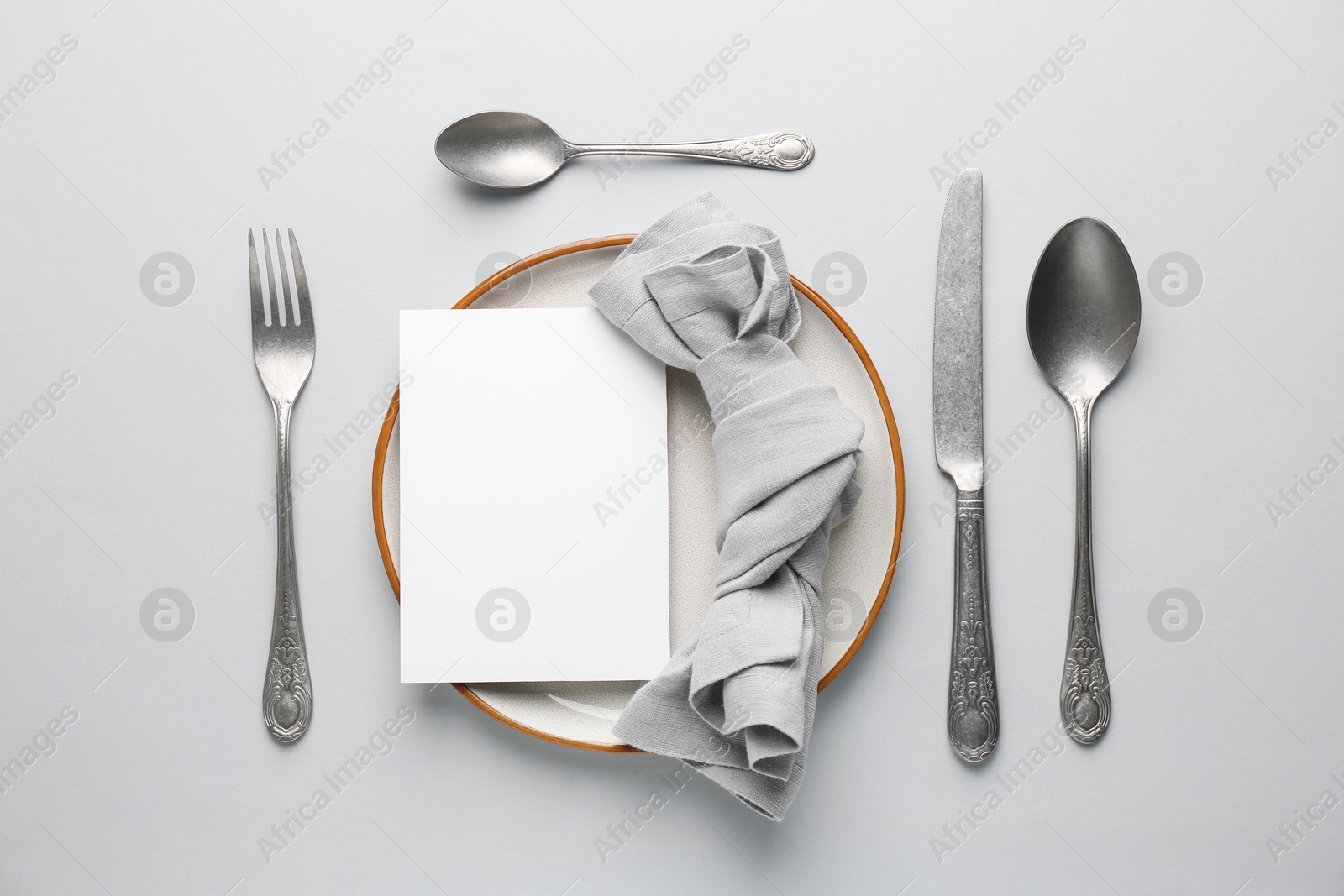 Photo of Empty menu, plate, cutlery and napkin on light grey background, flat lay. Mockup for design