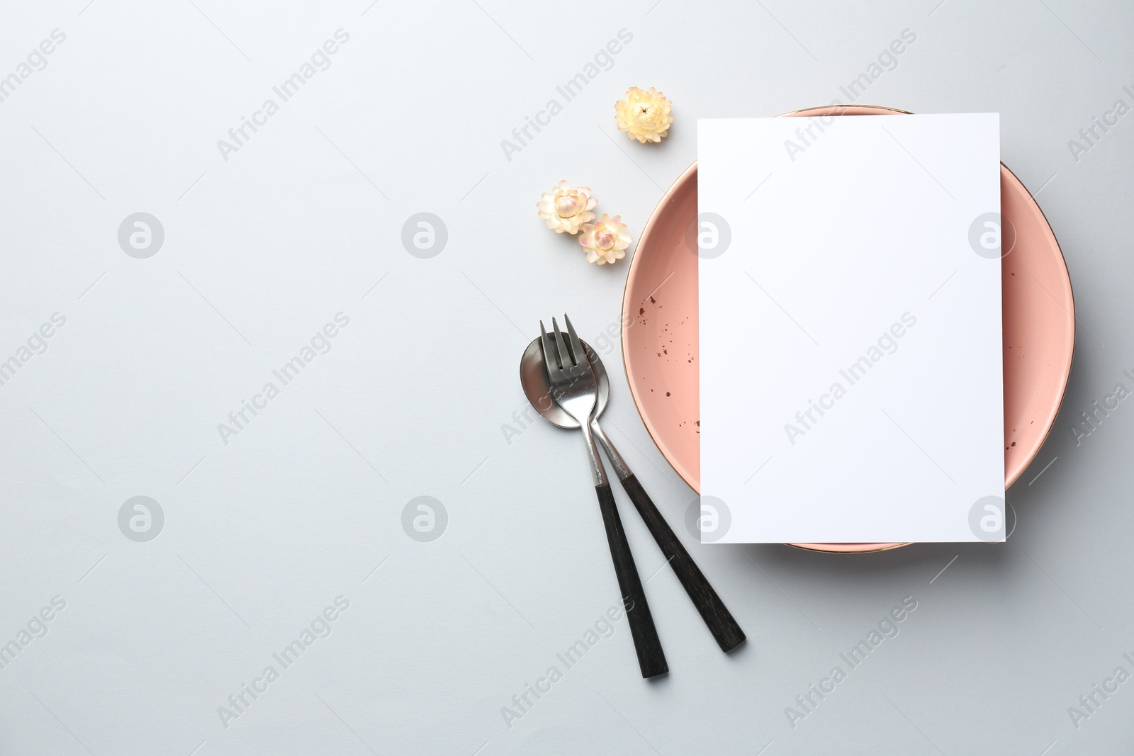 Photo of Empty menu, plate, cutlery and flowers on light grey background, top view. Mockup for design