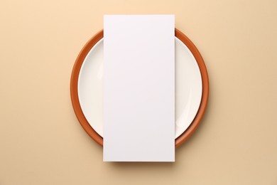 Photo of Empty menu and plates on beige background, top view. Mockup for design