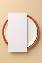 Photo of Empty menu and plates on beige background, top view. Mockup for design