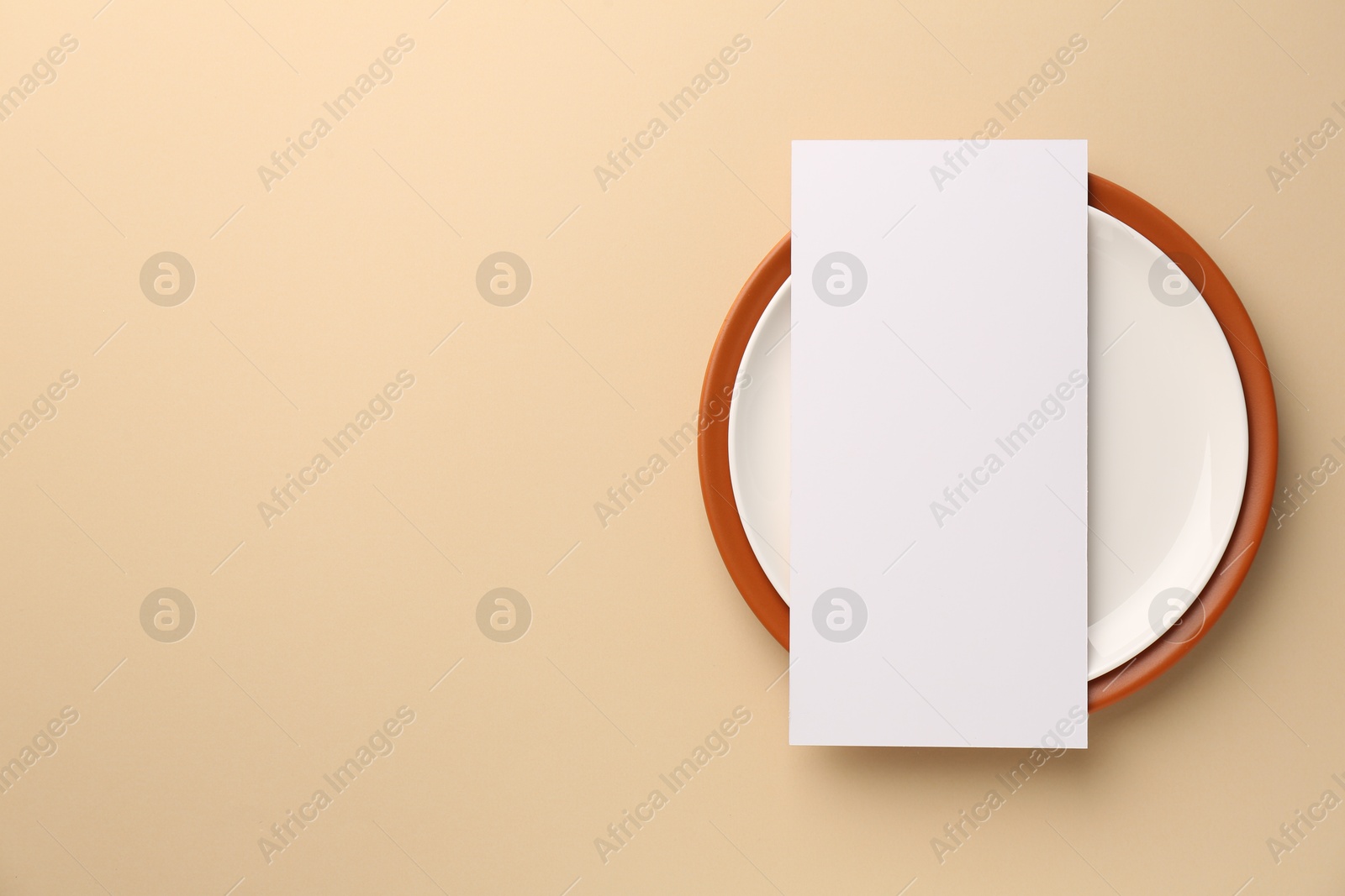 Photo of Empty menu and plates on beige background, top view. Mockup for design