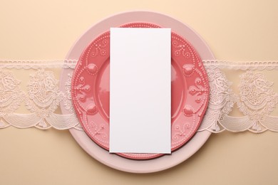 Empty menu and plates on beige background, top view. Mockup for design