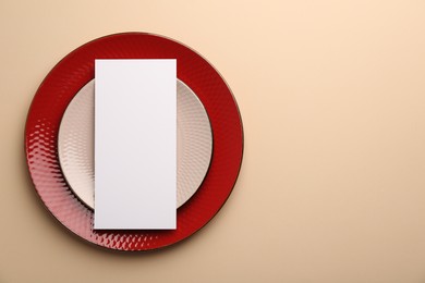 Empty menu and plates on beige background, top view. Mockup for design