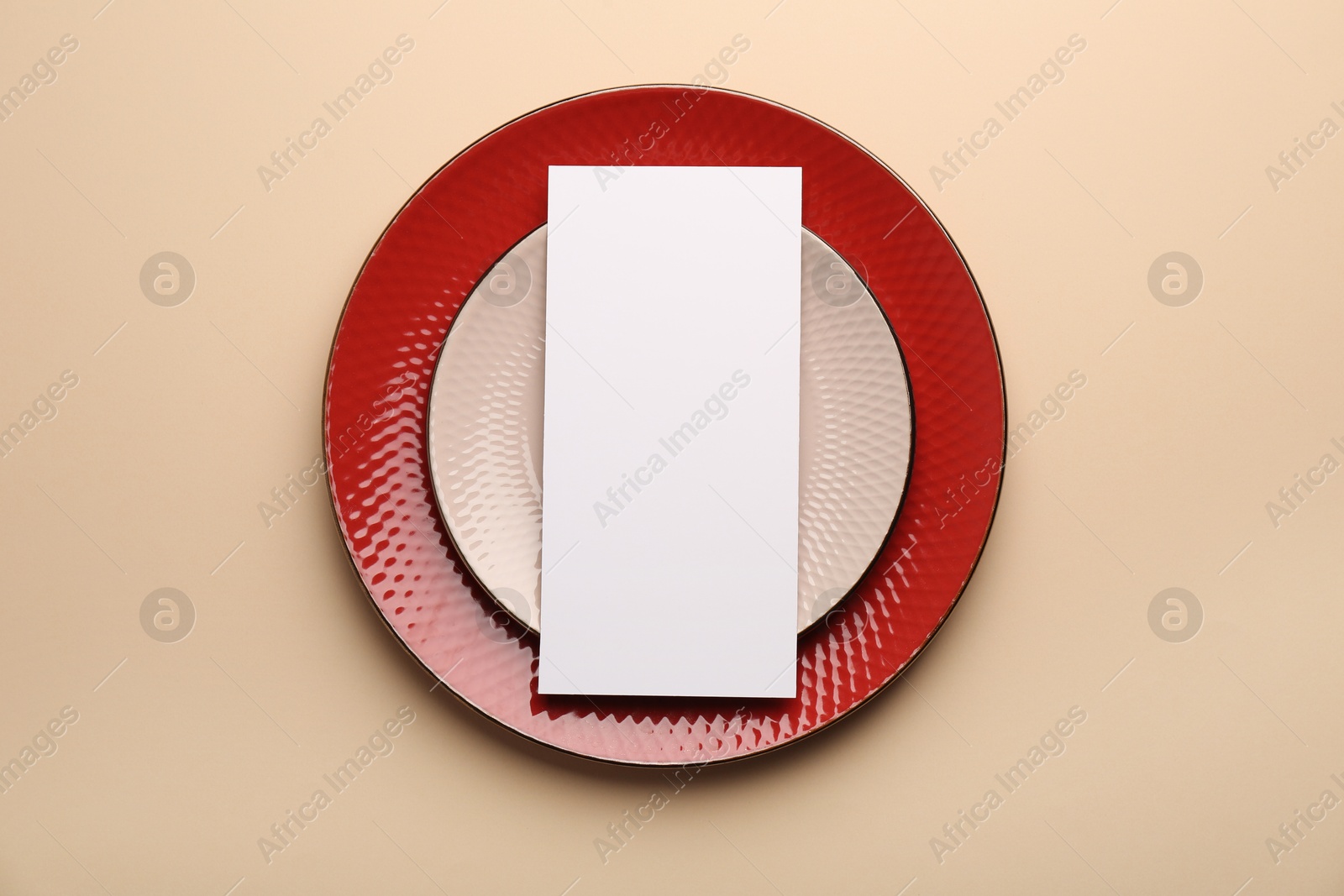 Photo of Empty menu and plates on beige background, top view. Mockup for design