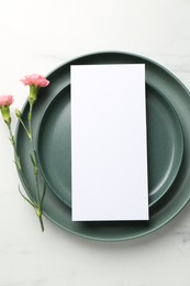 Empty menu, plates and floral decor on white marble table, top view. Mockup for design