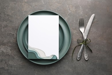 Photo of Empty menu, plates, cutlery and floral decor on grey table, top view. Mockup for design