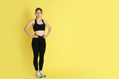 Woman with slim body posing on yellow background, space for text