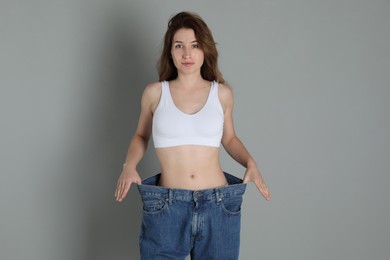 Woman in big jeans showing her slim body on grey background