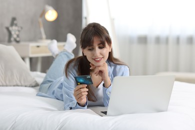 Online banking. Smiling woman with credit card and laptop paying purchase at home