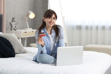 Photo of Online banking. Smiling woman with credit card and laptop at home