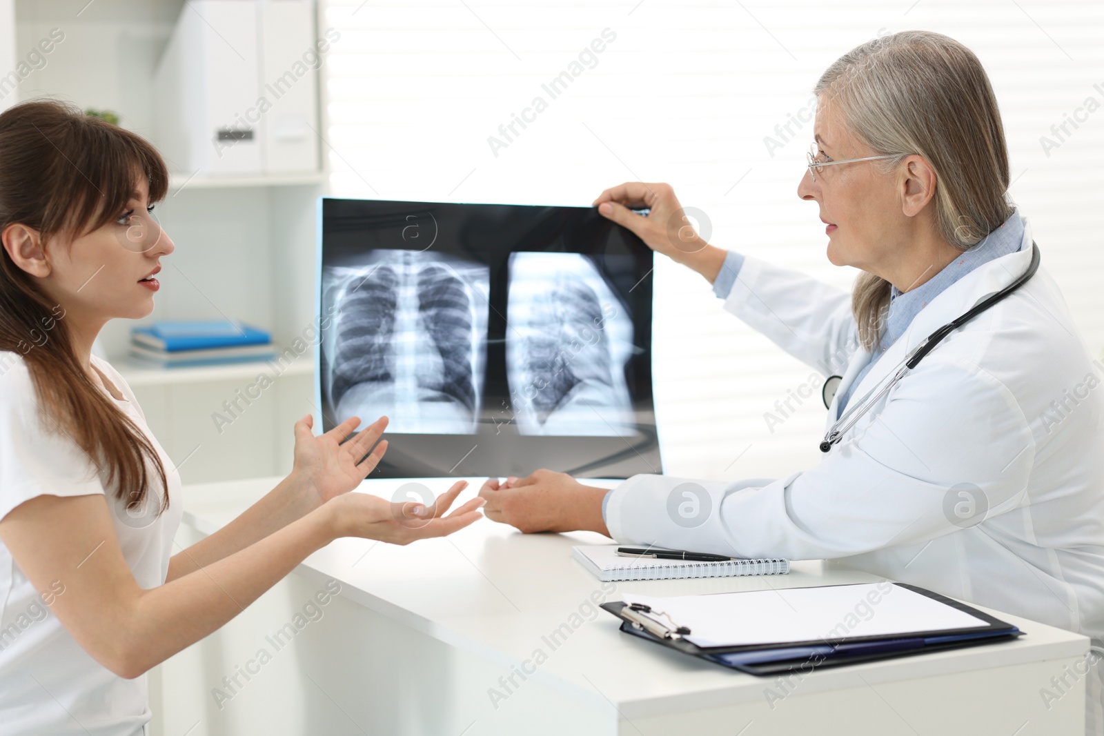 Photo of Lung disease. Doctor showing chest x-ray to her patient in clinic