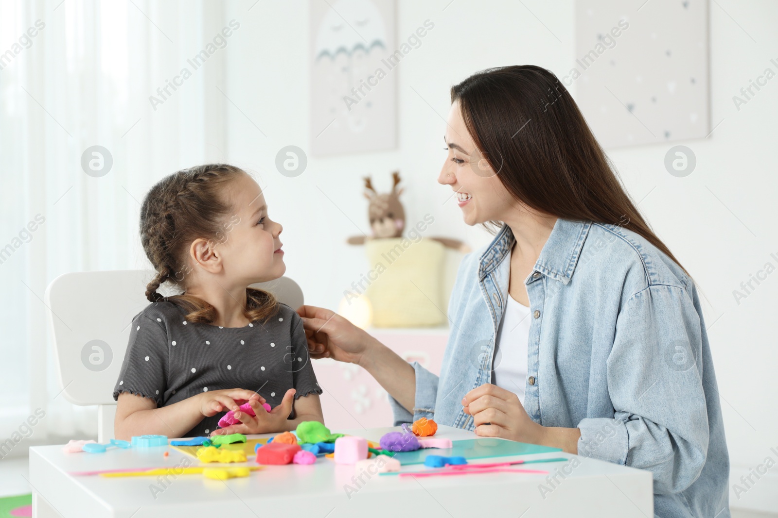 Photo of Play dough activity. Smiling mother with her daughter at table indoors