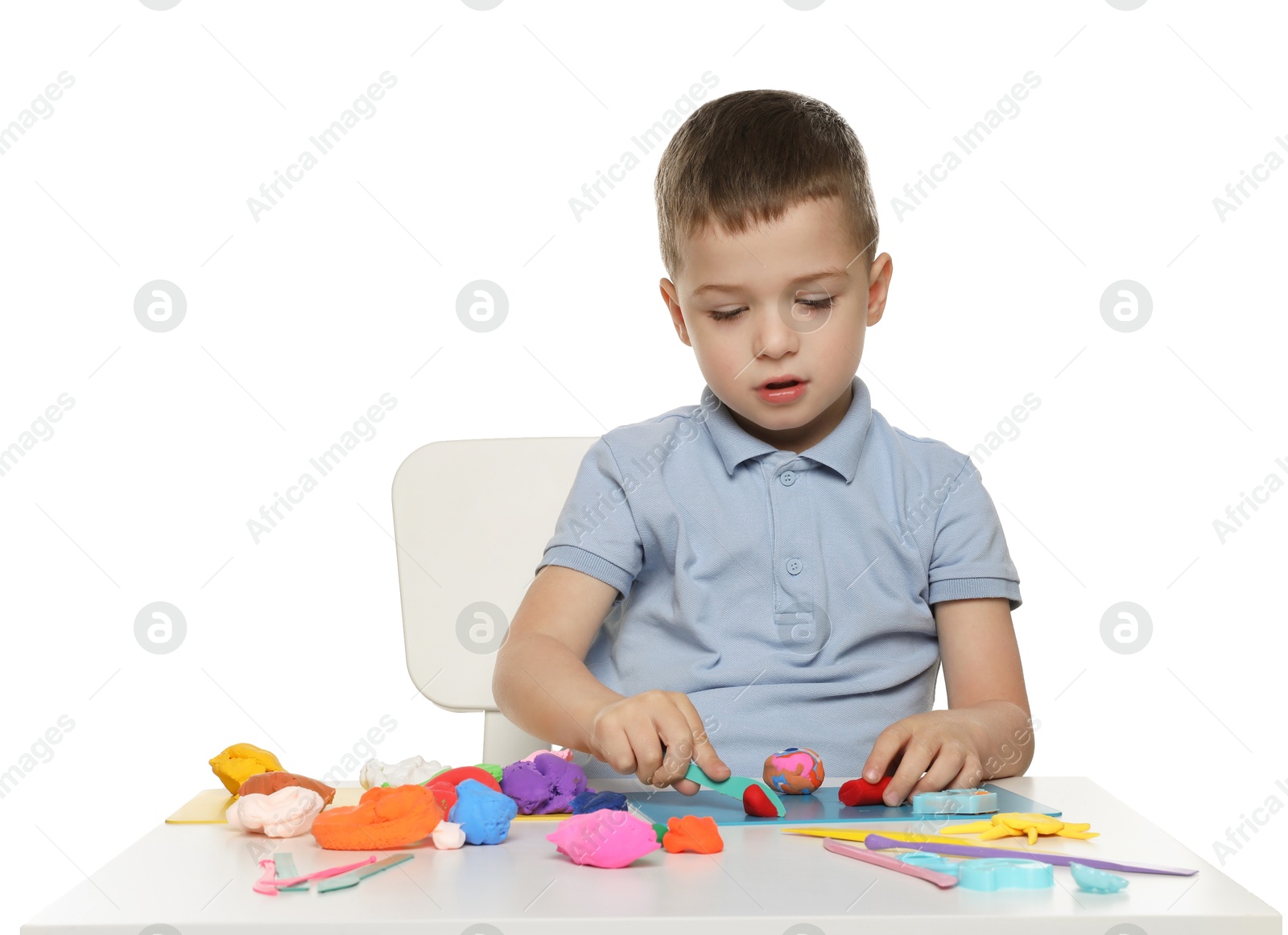 Photo of Little boy sculpting with play dough at table on white background