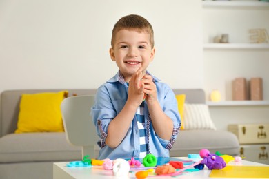 Photo of Smiling boy sculpting with play dough at table in kindergarten