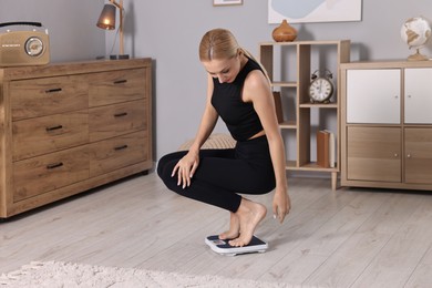 Woman measuring weight on floor scale at home