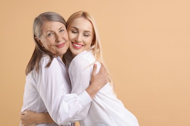 Photo of Family portrait of young woman and her mother on beige background. Space for text