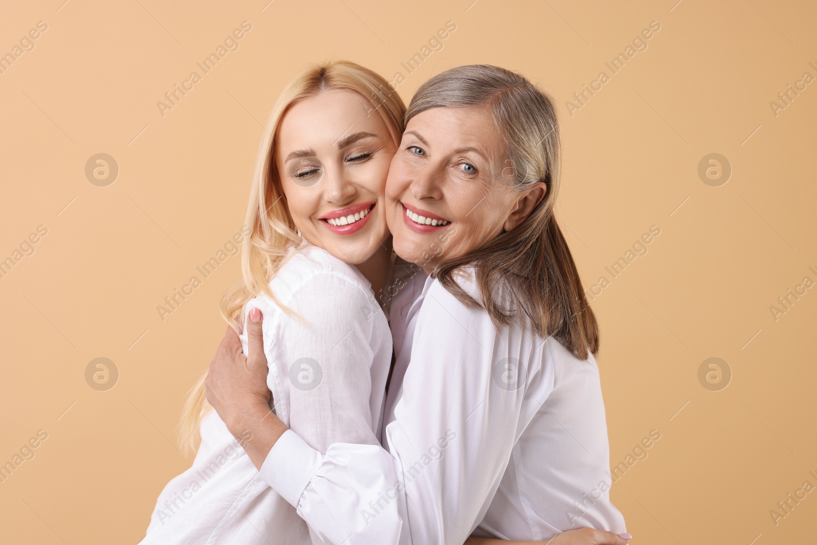 Photo of Family portrait of young woman and her mother on beige background