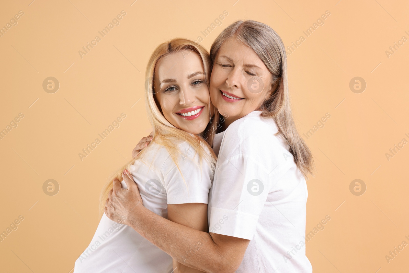 Photo of Family portrait of young woman and her mother on beige background