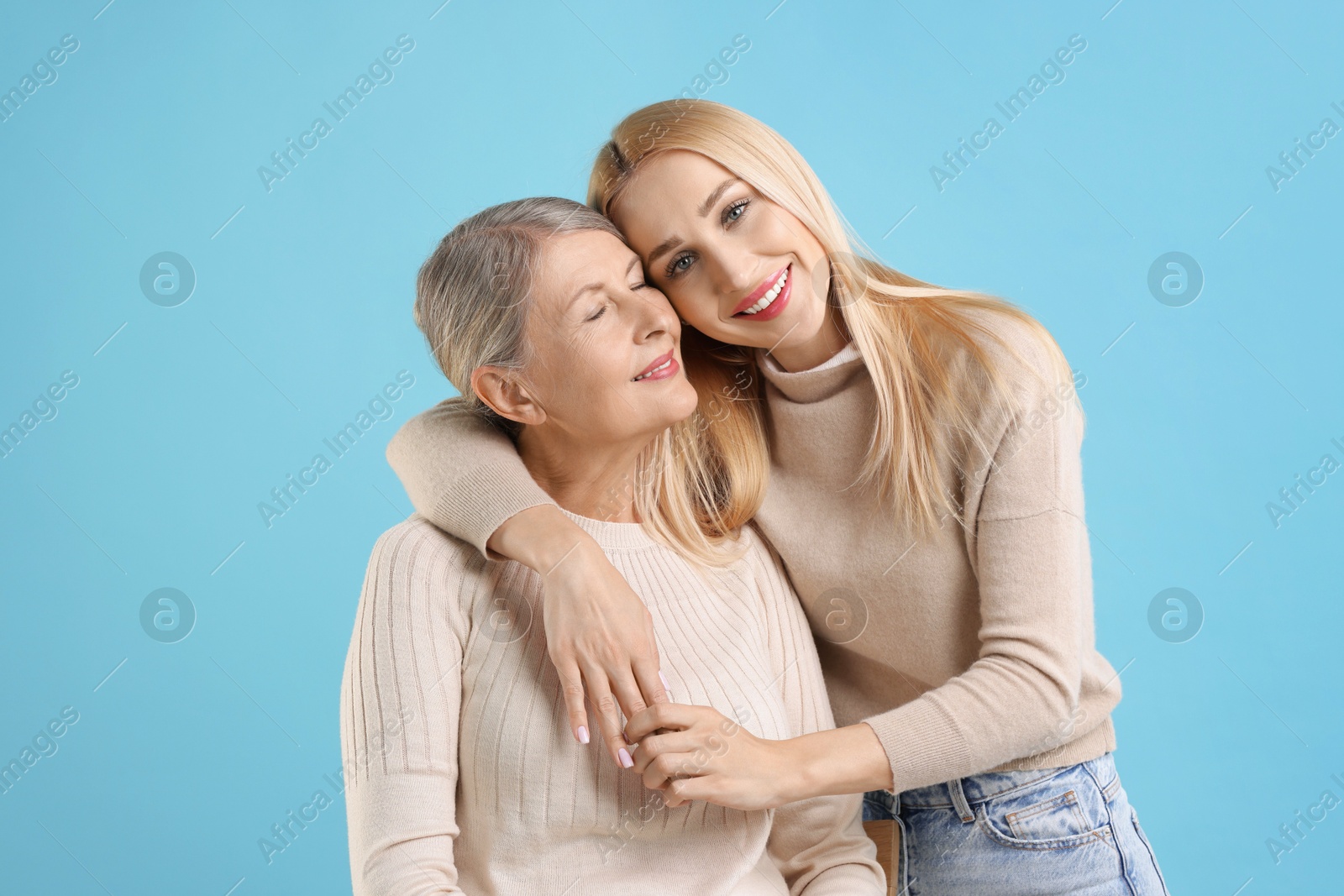 Photo of Family portrait of young woman and her mother on light blue background