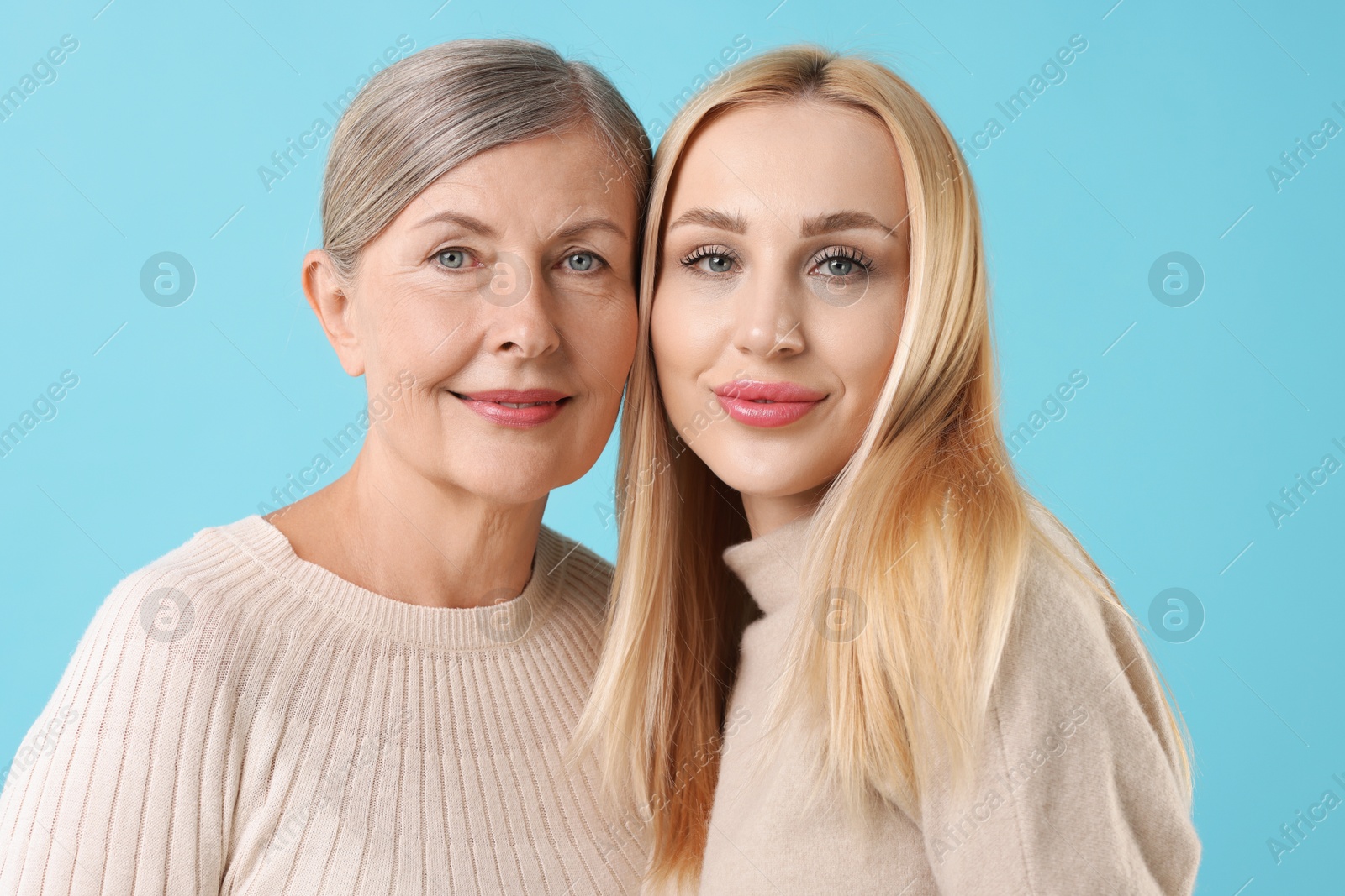 Photo of Family portrait of young woman and her mother on light blue background