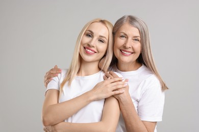 Photo of Family portrait of young woman and her mother on light grey background