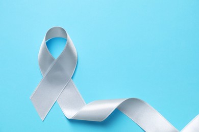 International Psoriasis Day. Ribbon as symbol of support on light blue background, top view. Space for text