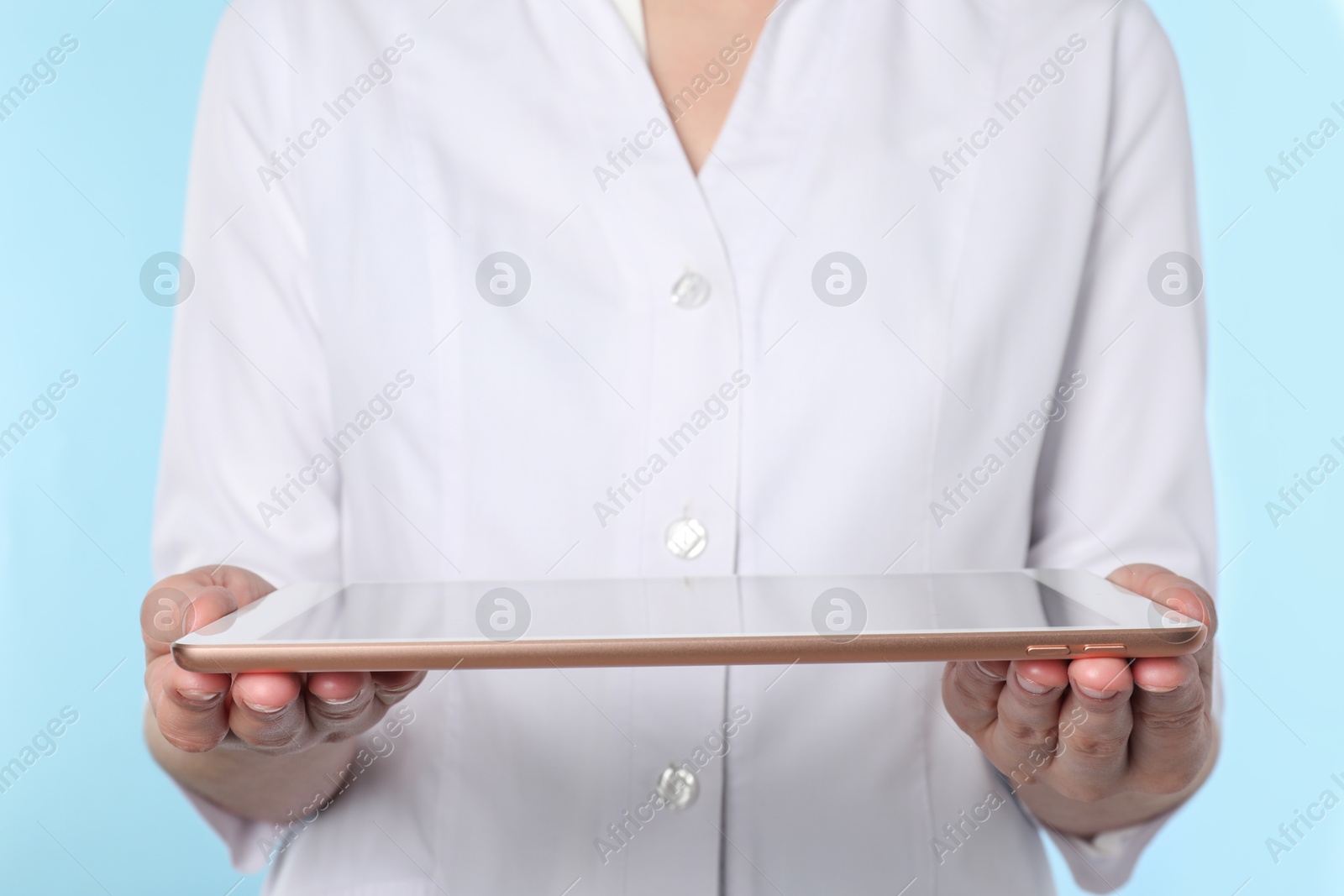 Photo of Doctor with tablet on light blue background, closeup