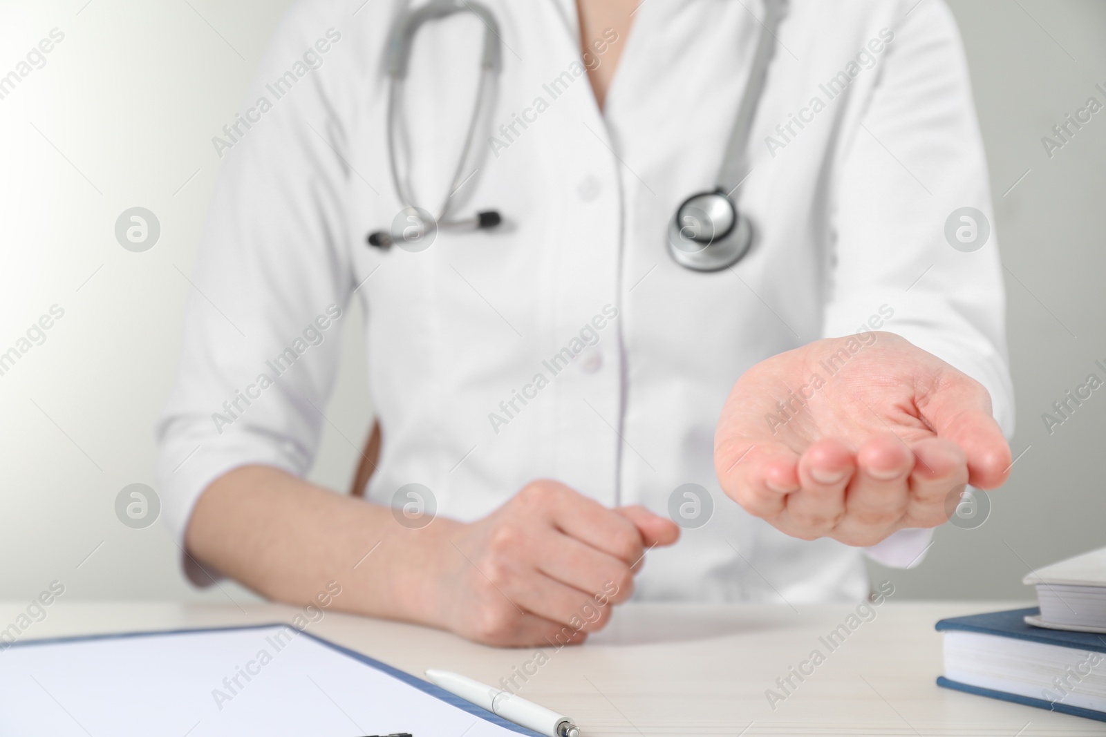 Photo of Doctor holding something at wooden table, closeup