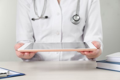 Photo of Doctor with tablet at wooden table, closeup