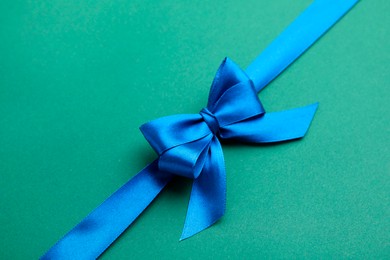 Blue satin ribbon with bow on green background